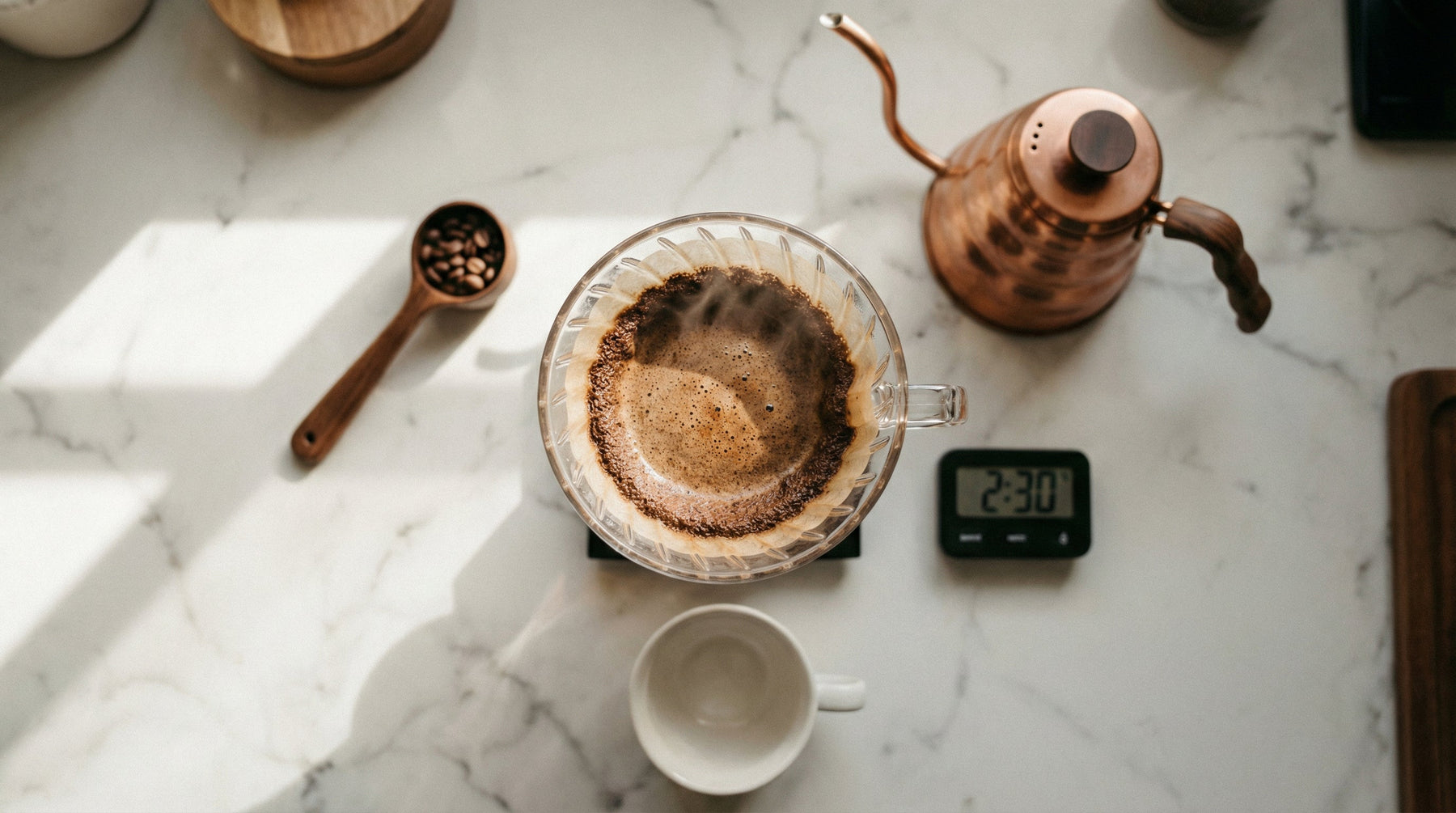 白いマーブルカウンターの上でドリップコーヒーを淹れる様子、V60ドリッパーと銅製ケトル