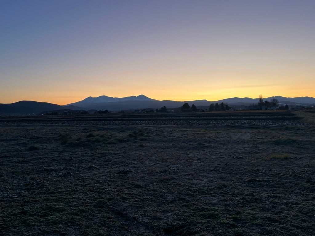 北海道東川町から見た大雪山の夕景。金色に染まる空と山々のシルエット。